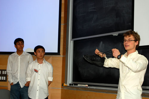 PRIMES reading group students Rohil 
            Prasad, Isaac Xia, and William Kuszmaul. Kuszmaul is 
            explaining the concept of trefoil, using his shoelaces.