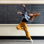Woman dancing in front of chalkboard.